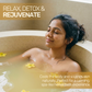 Woman relaxing in an herbal bath infused with yellow Avarampoo flowers, cooling the body and soothing skin naturally.