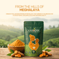 Aarogya Lakadong turmeric pouch on a wooden table with raw roots, featuring a scenic backdrop of misty Meghalaya hills.